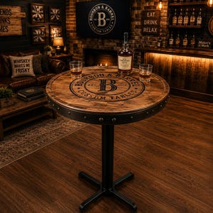 May include: A round pub table featuring a dark wood grain top with a black metal band and rivets around the edge. The center of the tabletop displays the text Bourbon & Barrel Est. 2013 with a large letter B. It has a black metal pedestal base.