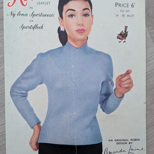 Peut inclure: Ancienne brochure "Robin" présentant une femme dans un pull bleu clair à col montant. La brochure comprend du texte, une illustration d'oiseau et le texte "Ny-lona Sportswear or Sportsfleck". Tour de poitrine 86-97 cm.