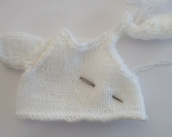 May include: White knitted sweater with a single sleeve, two needles, and loose threads.
