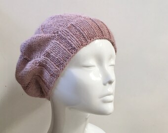 Puede incluir: Un gorro de punto rosa suave con una superficie ligeramente texturizada. El gorro se lleva en una cabeza de maniquí blanca.