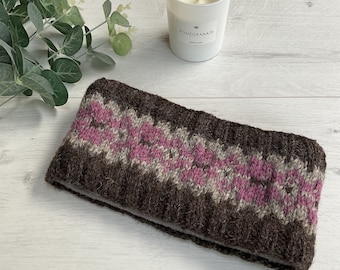 Puede incluir: Diadema de punto marrón y rosa con un patrón geométrico. La diadema está hecha de un hilo suave y texturizado. Una vela blanca con la palabra "Pomegranate" está en el fondo. Diseñado para mantener las orejas calientes.