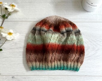 Könnte beinhalten: Eine gestrickte Mütze mit einem gestreiften Muster in Braun-, Grün- und Orangetönen. Die Mütze hat ein strukturiertes Strickmuster und einen umgeschlagenen Rand.