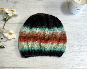 Könnte beinhalten: Eine schwarze Strickmütze mit horizontalen Streifen in Braun-, Orange- und Türkistönen.