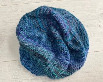 Könnte beinhalten: Eine blaue und grüne Strickmütze mit einem strukturierten Muster.