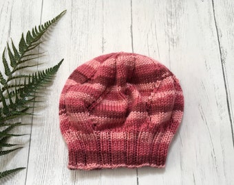 Puede incluir: Un gorro de punto de rayas rosas y blancas con un patrón texturizado.