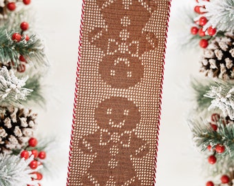 May include: A brown crocheted table runner with a red and white trim. The runner features a repeating pattern of three snowmen.