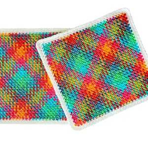 May include: Two colorful crocheted squares with a white border. The squares are made with a variety of colors, including red, orange, yellow, green, blue, and purple.