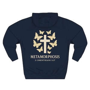 May include: Navy blue hoodie with a white cross and butterflies design. The text "METAMORPHOSIS 2 Corinthians 5:17" is printed below the cross. The hoodie has a hood and long sleeves.