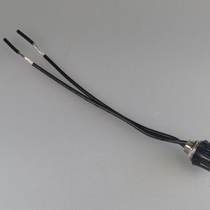May include: A black electrical switch with two black wires attached. The switch has a black plastic housing and a silver metal base.