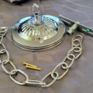 May include: Chrome ceiling light fixture with a chain, a decorative cover, and a mounting bracket. The fixture has a small green screw.
