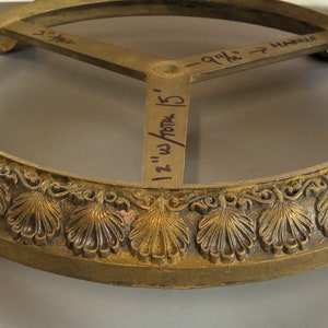 May include: Gold metal base with a round top and three legs. The base has a decorative design of leaves and a 12 inch diameter.