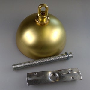 May include: Gold metal ceiling fixture with a round dome shape and a threaded rod. The fixture includes a mounting plate with a hole for attaching to a ceiling.