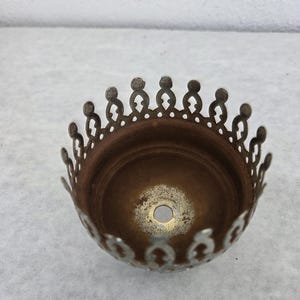 May include: A vintage-style metal lampshade component with a decorative, openwork crown-like edge. The interior is a warm, aged bronze color, and the rim is a silver-toned metal. A small hole is visible in the center.