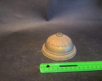 May include: A gold-toned metal lamp finial with a decorative floral design. The finial has a small hole in the center for attaching to a lampshade.