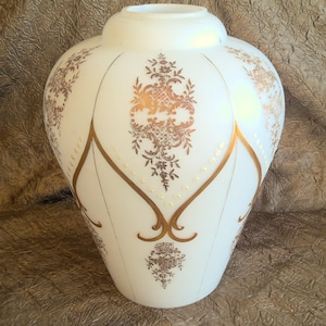 May include: White glass lampshade with a gold floral design. The lampshade is shaped like a vase and has a scalloped edge.