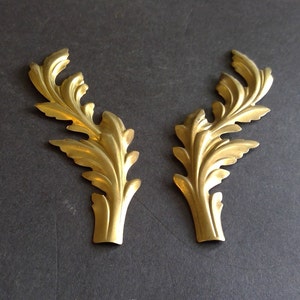 May include: Two gold-colored metal leaf-shaped decorative accents. The accents are intricately detailed and have a slightly curved shape.
