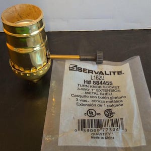 Peut inclure: Une douille à bouton rotatif à 3 voies avec une extension de 2,5 cm en métal doré avec un bouton noir. L'emballage comprend le texte "SERVALITE. L162U H# 884455 TURN KNOB SOCKET 3-WAY 1" EXTENSION METAL SHELL Casquillo con botón giratorio 3 vias, coraza metálica Extensión de 1 pulgada 0 39008 77304 3 QUANTITY 1 Made in China".