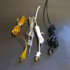 May include: Assortment of electrical cords in various colors, including yellow, gray, white, and black. Each cord is bundled and features a plug at one end. The cords are for electrical devices.