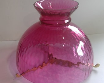 Könnte beinhalten: Ein rosa gläserner Lampenschirm mit gerippter Textur und drei Metallhalterungen.