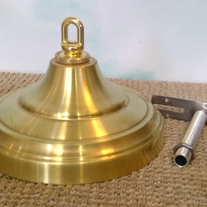 Peut inclure: Un luminaire de plafond en laiton avec une bague décorative et un tuyau fileté pour suspendre un luminaire. Le luminaire est sur un tapis brun.