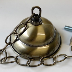 May include: A brass ceiling light fixture with a chain and a decorative canopy. The fixture has a threaded rod for attaching to a ceiling.