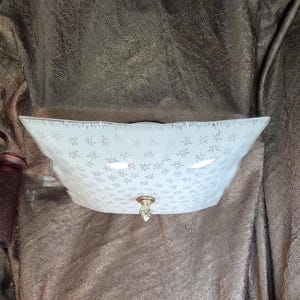 May include: A square, white, frosted glass ceiling light fixture featuring a repeating pattern of small, etched starburst designs. The center of the glass shade is secured by a decorative, clear, faceted glass finial with a brass-toned metal base.