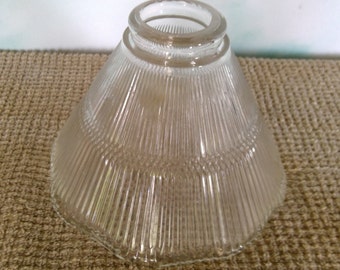 May include: Clear glass lampshade with a ribbed design. The shade is cone-shaped and has a wide opening at the top.