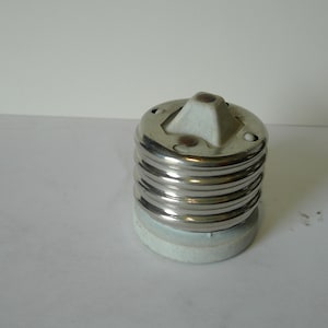 May include: A white ceramic light bulb socket with a silver metal threaded ring. The socket has a center post for the bulb.