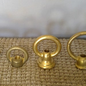 May include: Six brass ceiling fixture hardware pieces, including a decorative finial, a ring with a small ball, and four different sized rings.