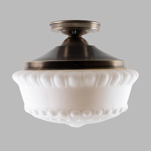May include: A semi-flush mount ceiling light fixture featuring a dark bronze metal canopy and a wide, bowl-shaped white frosted glass shade. The glass shade displays a decorative scalloped edge pattern around the top and bottom sections.