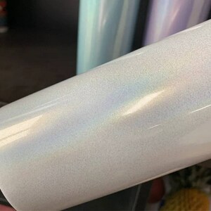 Puede incluir: Un vaso blanco iridiscente con un acabado liso y brillante. El vaso tiene un brillo sutil y un ligero efecto arco&iacute;ris.
