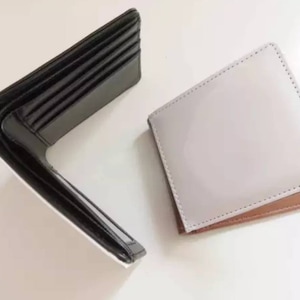 May include: Two wallets, one black and one white, are shown open. The black wallet has multiple card slots and is made of leather. The white wallet is made of a smooth material and has a brown trim.