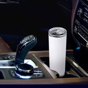 Puede incluir: Un vaso blanco de acero inoxidable con tapa, colocado en el portavasos de un coche.