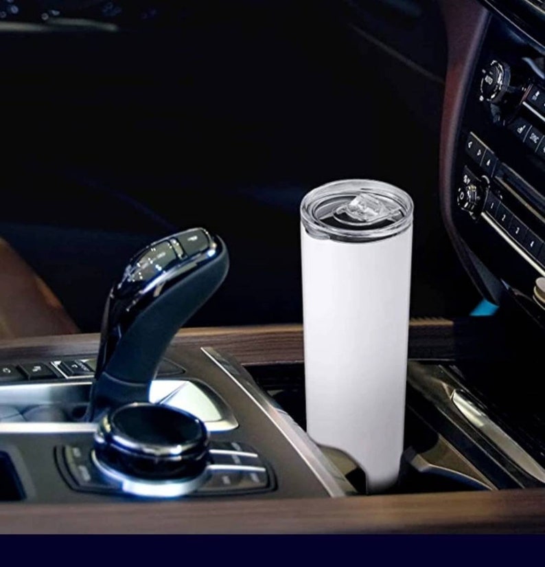 Puede incluir: Un vaso blanco de acero inoxidable con tapa, colocado en el portavasos de un coche.