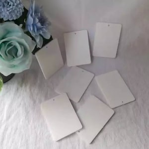 May include: Seven blank white rectangular gift tags with a hole punched in the top center of each tag.