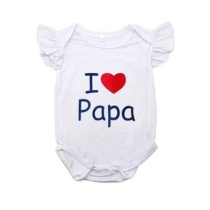 May include: White baby onesie with a red heart and the text "I love Papa" in blue.