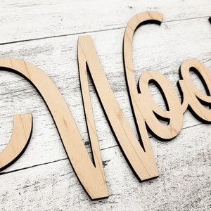 May include: Wooden word sign that says "Wood" in a cursive font. The sign is made of light brown wood and has a natural finish.