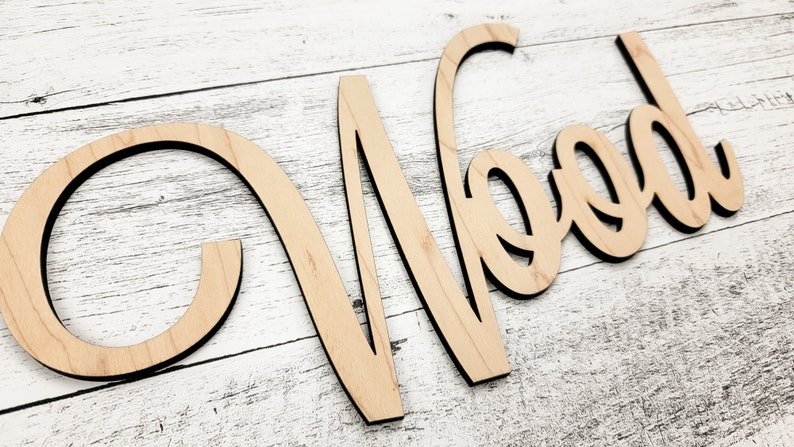 May include: Wooden word sign that says "Wood" in a cursive font. The sign is made of light brown wood and has a natural finish.