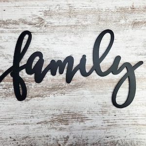May include: Black metal wall decor with the word "family" written in a cursive script.