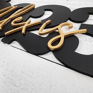 May include: Black and gold wooden sign with the name "Alexis" and the number "23" in a modern font.