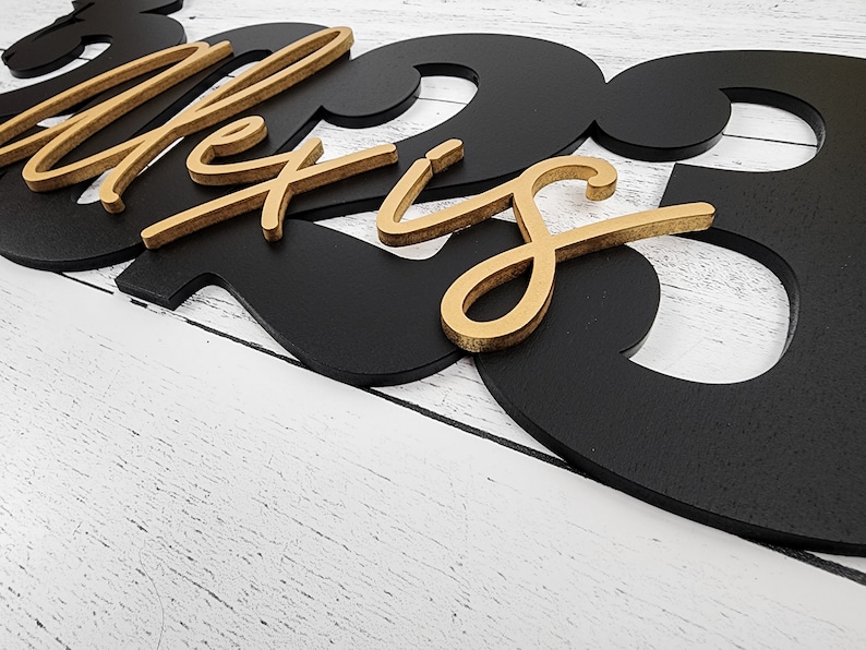 May include: Black and gold wooden sign with the name "Alexis" and the number "23" in a modern font.