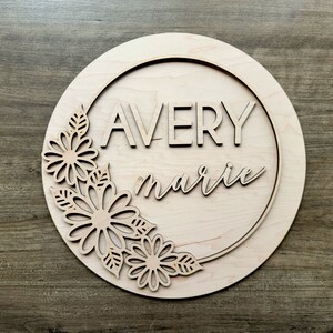 May include: A wooden round sign with a floral design and the names "Avery marie" in a decorative font.