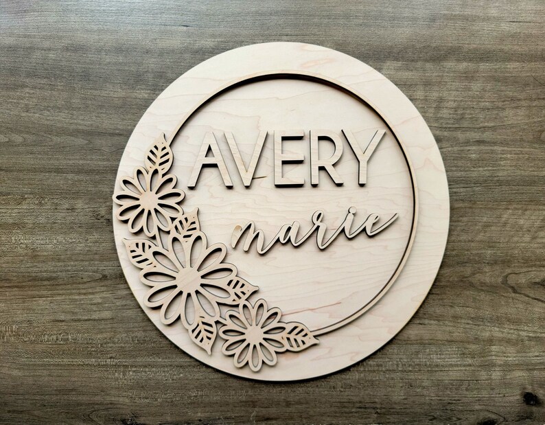 May include: A wooden round sign with a floral design and the names "Avery marie" in a decorative font.