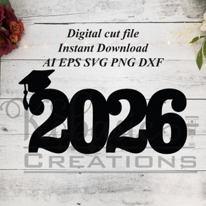 May include: Black silhouette of the year 2026 with a graduation cap on top. The text "CREATIONS" is below the numbers. The image is on a white wood background.