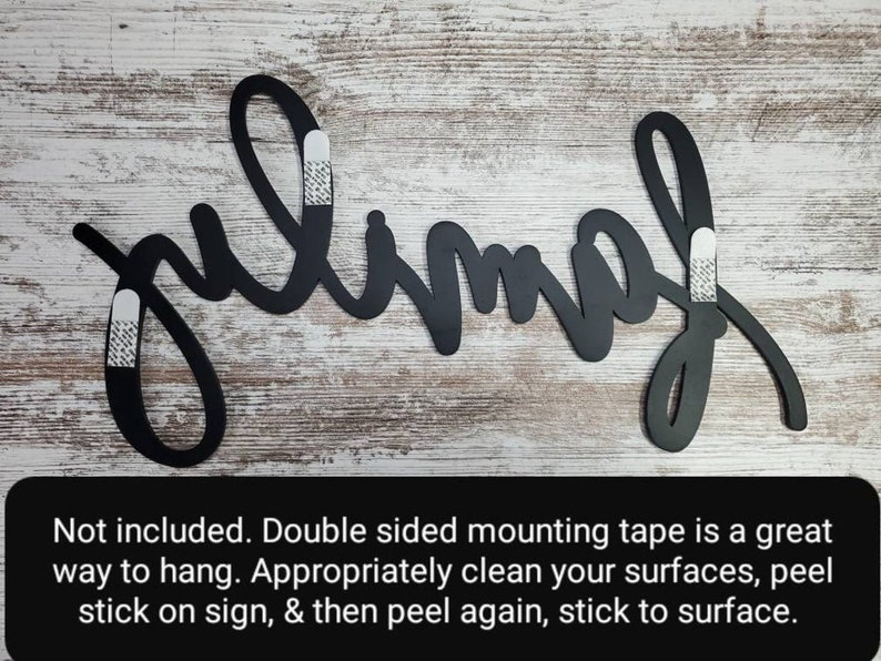 May include: Black metal wall decor with the word "julimah" written in a cursive script. Three white adhesive strips are attached to the back of the sign for hanging.