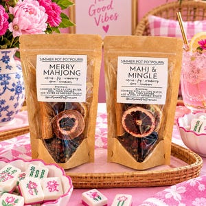May include: Two brown paper pouches of simmer pot potpourri labeled Merry Mahjong and Mahj & Mingle, containing dried citrus slices, cinnamon sticks, and spices. The pouches feature white labels with black text and instructions for use.