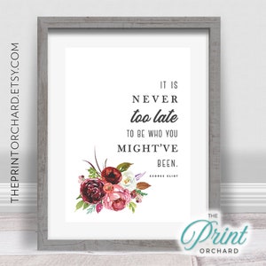 May include: A printable quote with a floral design in shades of pink, red, and green. The quote reads "It is never too late to be who you might've been." - George Eliot. The print is framed in a gray frame.