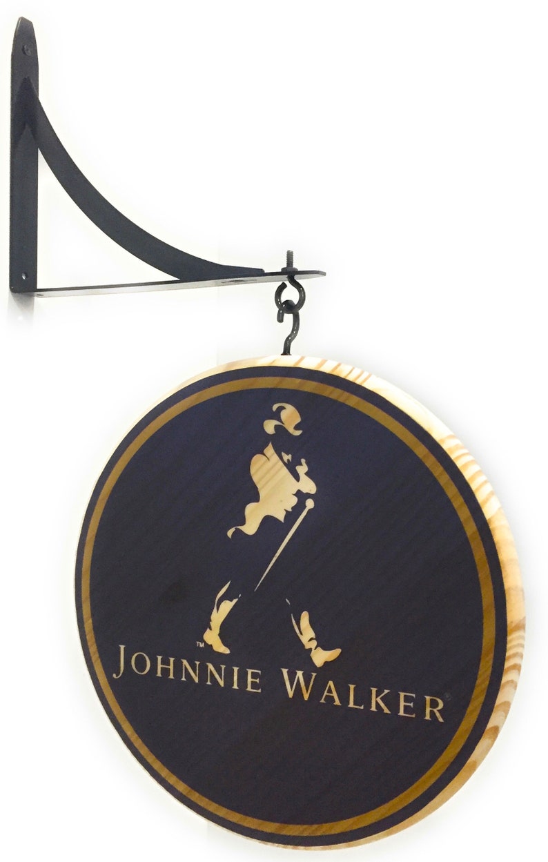 May include: A round wooden sign with a gold border and a black background. The sign features the Johnnie Walker logo, which includes a man in a top hat walking with a cane. The sign is hanging from a black metal bracket.