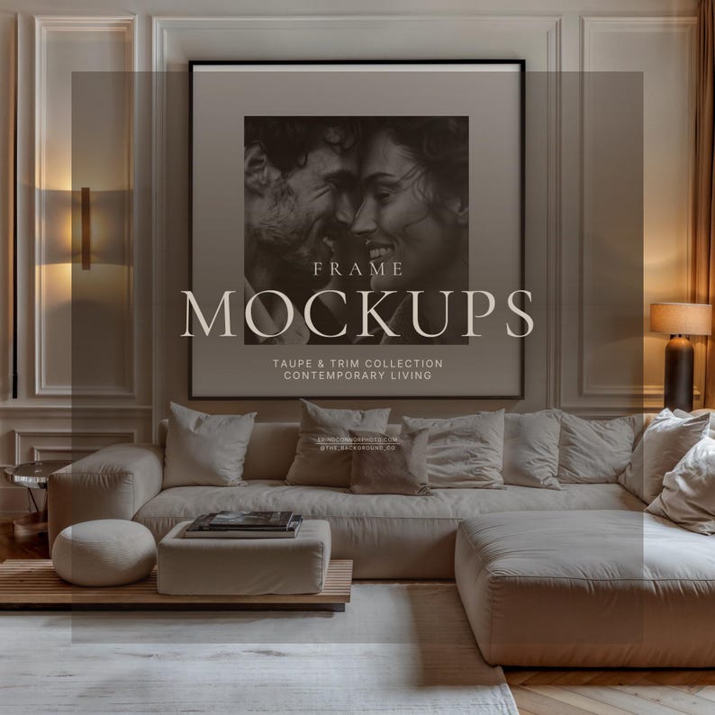 Contemporary taupe living room wall art mockup with large vertical black frame, cream sofa, wall sconces, coffee table, and black and white portrait