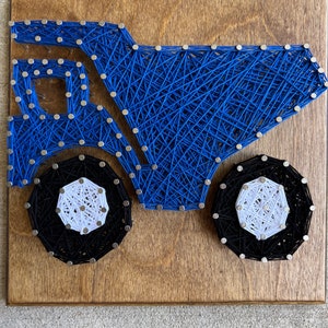 May include: Blue and black string art of a dump truck on a wooden background.